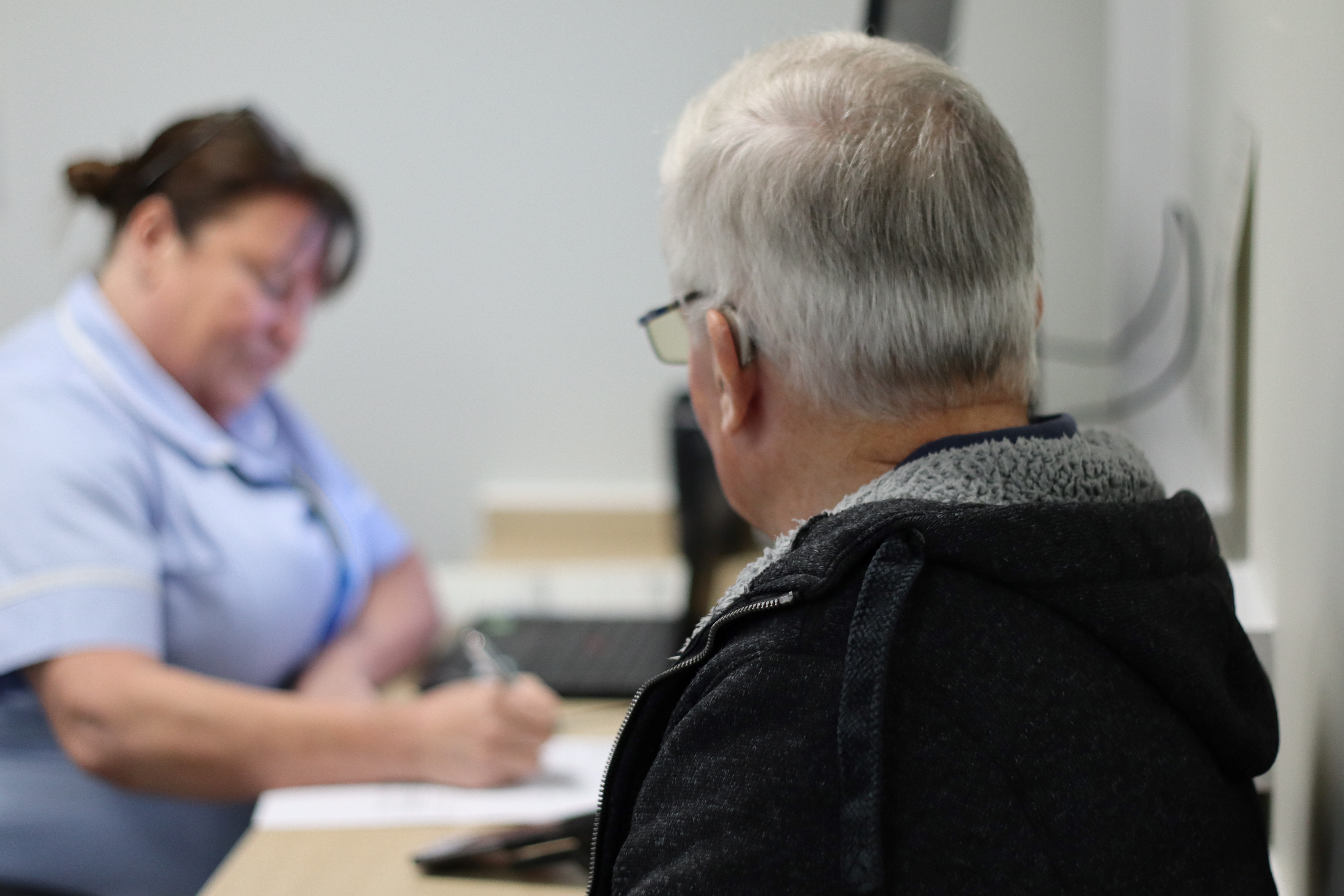 Stephen Campion inside the clinic speaking to a Health Care Assistant